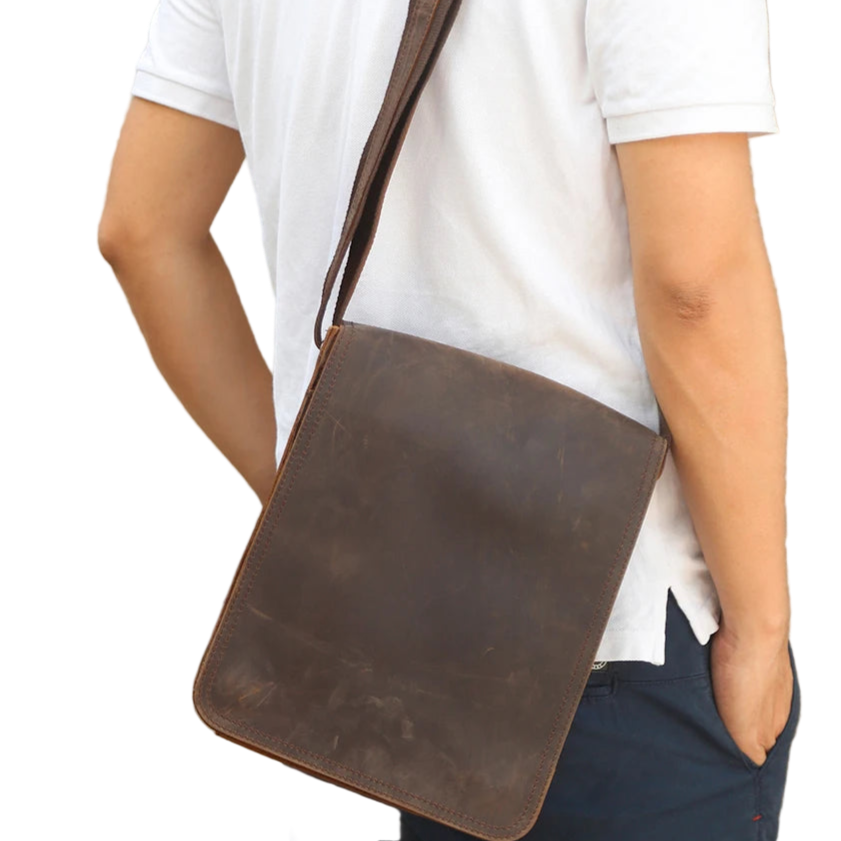 Person wearing a brown leather crossbody bag on a white background