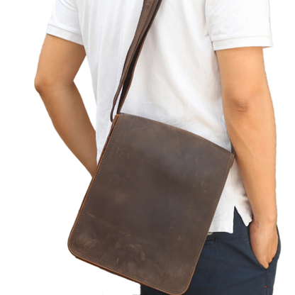 Person wearing a brown leather crossbody bag on a white background