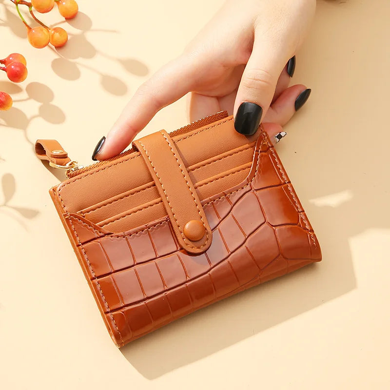 Brown textured wallet held by a hand with black nail polish on a beige background