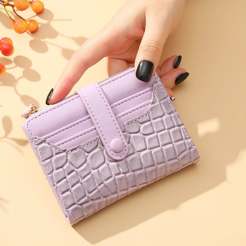 Hand holding a purple textured wallet on a beige background with berries.