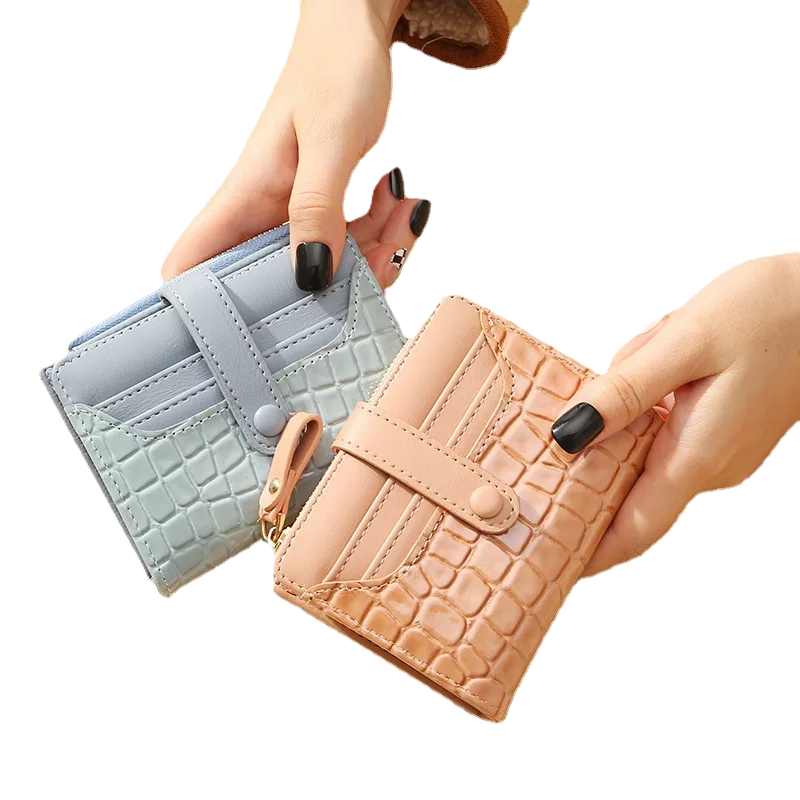 Two_wallets_one_light_blue_and_one_beige_with_crocodile_texture_held_by_a_hand